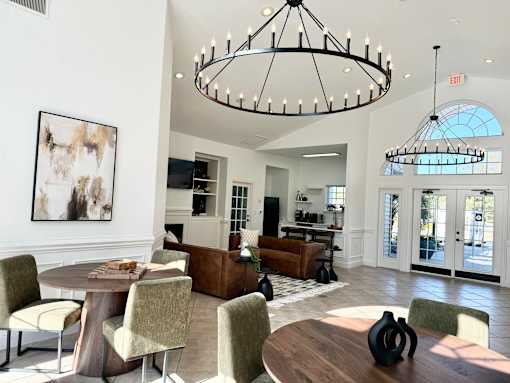 A large, well-lit room with a dining table and chairs, a couch, and a chandelier.