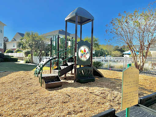 A playground with a sign that says "Playground Rules" and a slide.