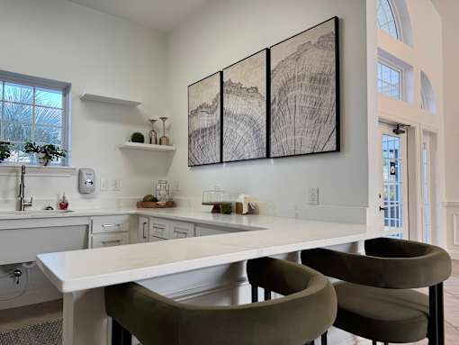 A modern kitchen with a large island and two chairs.