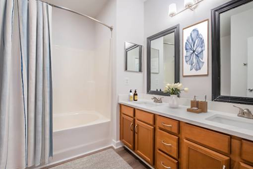 A bathroom with a white tub and wooden cabinets.
