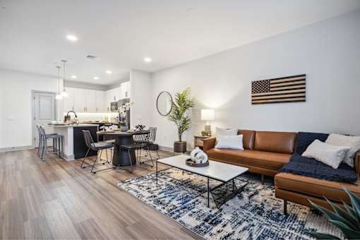A modern living room with a dining area and a kitchen in the background.
