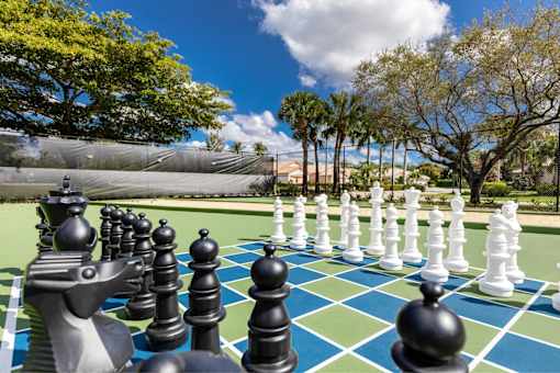 A giant chess set is set up on a green and blue checkered field.