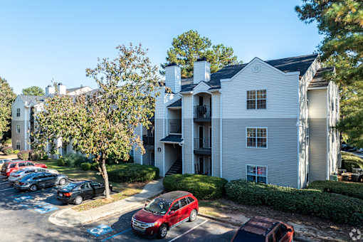 A white building with a red car parked in front.