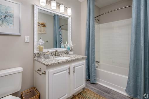 A bathroom with a white sink and a large mirror.