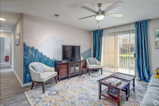 A living room with a television, two chairs, a coffee table, and a rug.