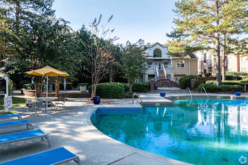 A pool with a yellow umbrella and blue loungers.