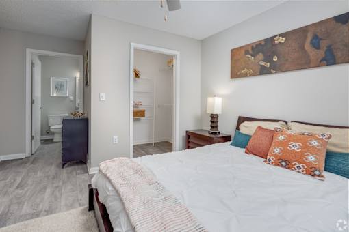 A bedroom with a bed, a nightstand, and a painting on the wall.