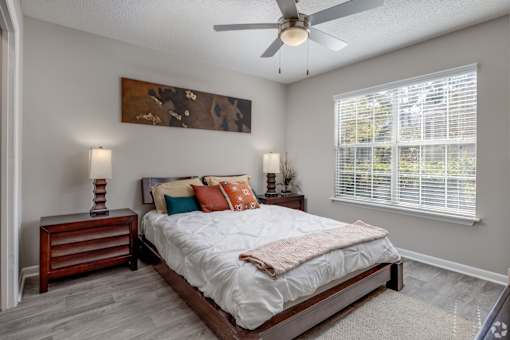 A bedroom with a bed, nightstand, and a painting on the wall.
