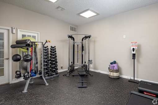 A gym room with a variety of equipment including weights and cardio machines.