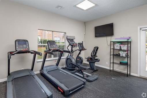 A room with a treadmill, elliptical trainer, and stationary bike.
