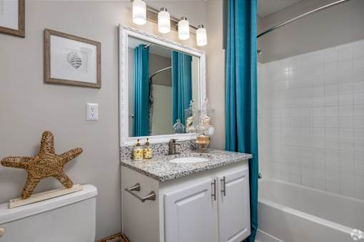 A bathroom with a white toilet, a sink with a mirror above it, and a blue shower curtain.