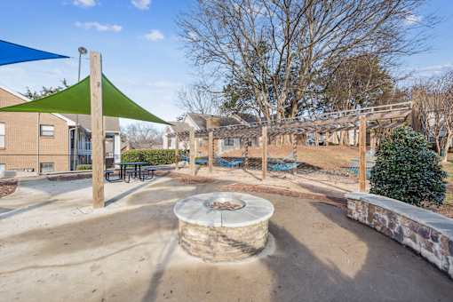 A playground with a green shade sail and a sand pit.