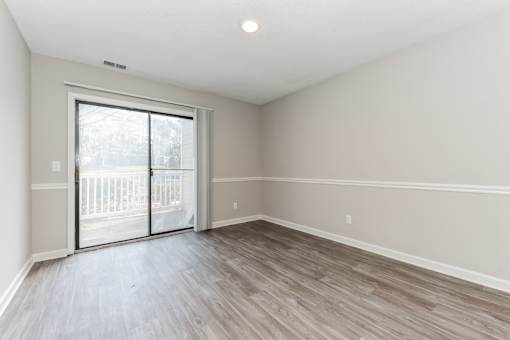 A room with a sliding glass door and wood flooring.