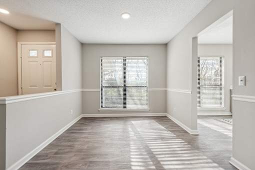 A room with a wooden floor and a window with blinds.