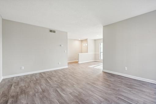 A large empty room with wood flooring and white walls.