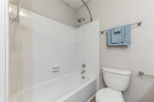 A white bathroom with a toilet, tub, and towel rack.