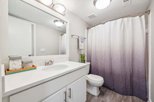 A white bathroom with a toilet, sink, and shower.
