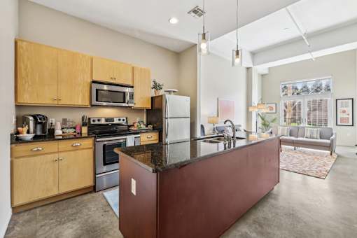 Three-Bedroom Apartments in Nashville, TN - The Marquee at Belle Meade - Modern Kitchen With Black Granite Island, Stainless Steel Appliances, Pendant Lighting, and Polished Concrete Floors.