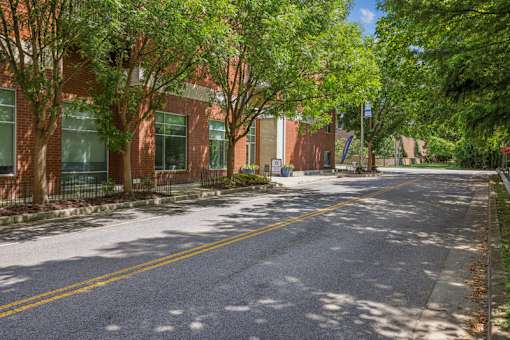 A tree-lined street with a brick building on the side.