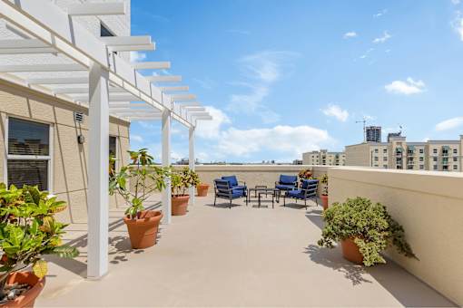 A patio with a white pergola and blue chairs.