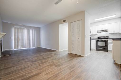 A spacious living room with a kitchen area in the background.
