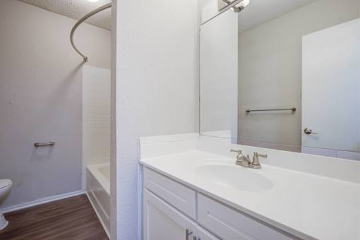 A white bathroom with a toilet, sink, and mirror.