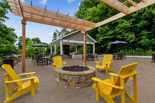 A patio with yellow chairs and a fire pit.