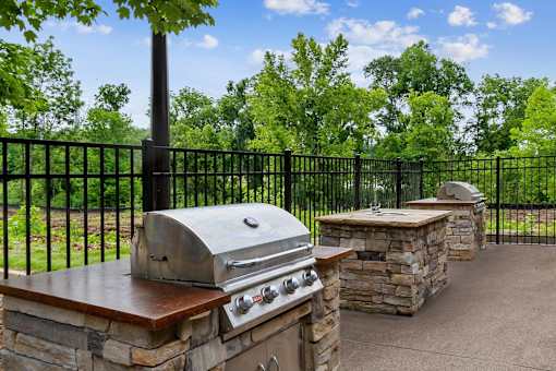 A black metal fence surrounds a stone and wood outdoor kitchen.
