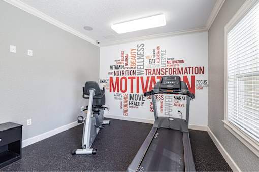 A treadmill in a room with a wall covered in words related to fitness and health.