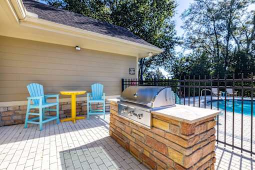A patio with a grill and chairs.