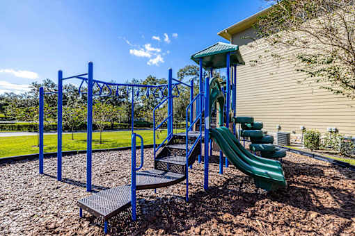 A playground with a blue swing set and a green slide.
