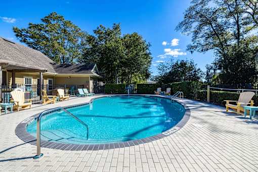 A round swimming pool surrounded by a wooden deck and lounge chairs.