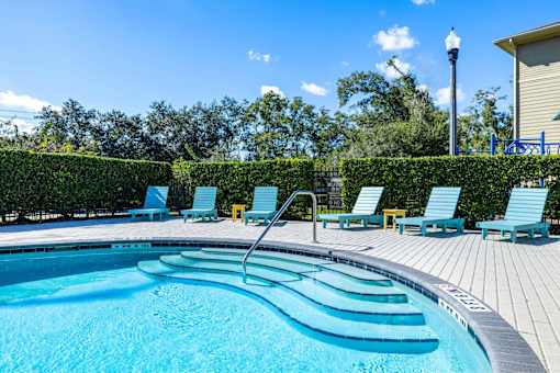 A swimming pool with blue water and lounge chairs.
