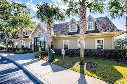A house with a driveway and palm trees in front.