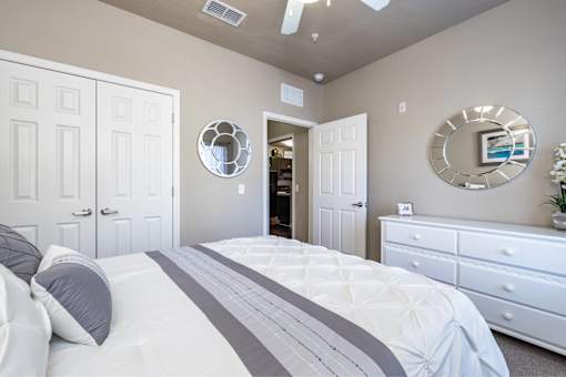 A bedroom with a large bed, two dressers, and a mirror on the wall.