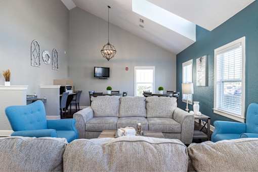 A living room with a grey couch and blue chairs.