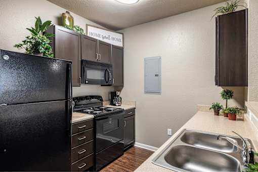 A kitchen with black appliances and a white wall.