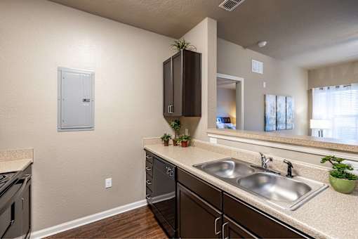 A kitchen with a sink, stove, and cabinets.