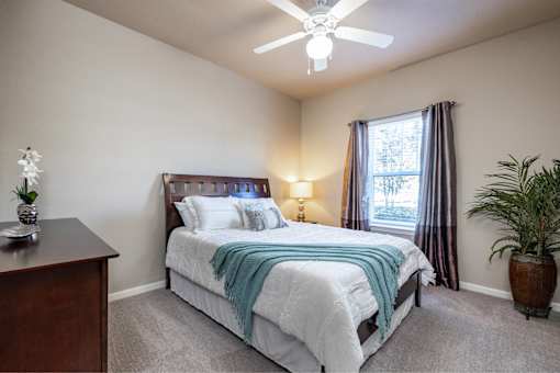 A bedroom with a bed, nightstand, and window.