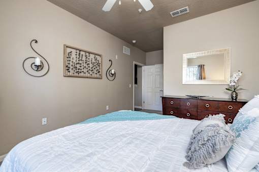 A bedroom with a large bed and a dresser with a mirror above it.