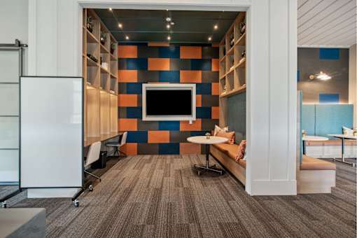 A modern office space with a white fridge, a television, and a bench.