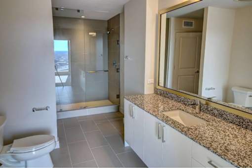 A bathroom with a toilet, sink, and mirror.
