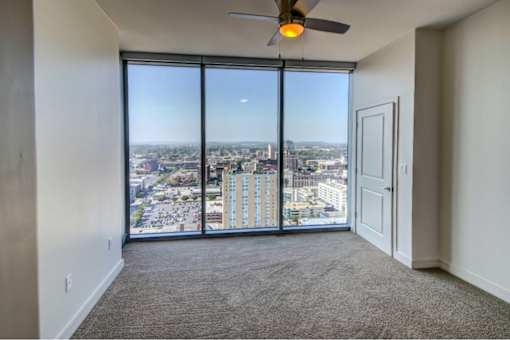 A room with a ceiling fan and a view of the city.