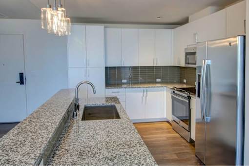 A kitchen with a granite counter top and stainless steel appliances.