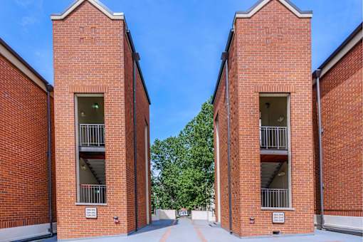 two red brick buildings with balconies and a blue sky