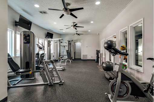 a gym with exercise equipment and a ceiling fan