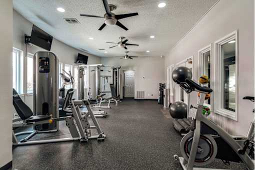 a gym with exercise equipment and a ceiling fan