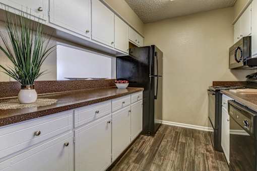 A Dishwasher, garbage disposal & frost-free refrigeratorwith a black refrigerator and white cabinets.