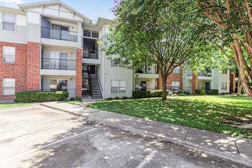 Apartment complex with a parking lot in front.
