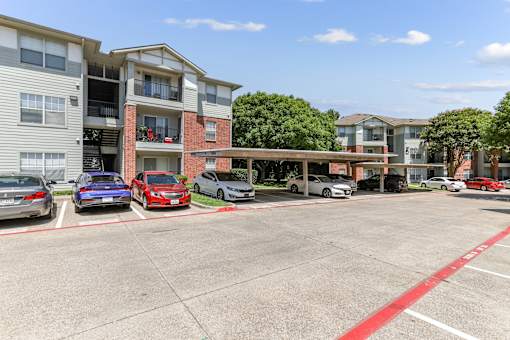 A parking lot with cars and apartment buildings in the background.